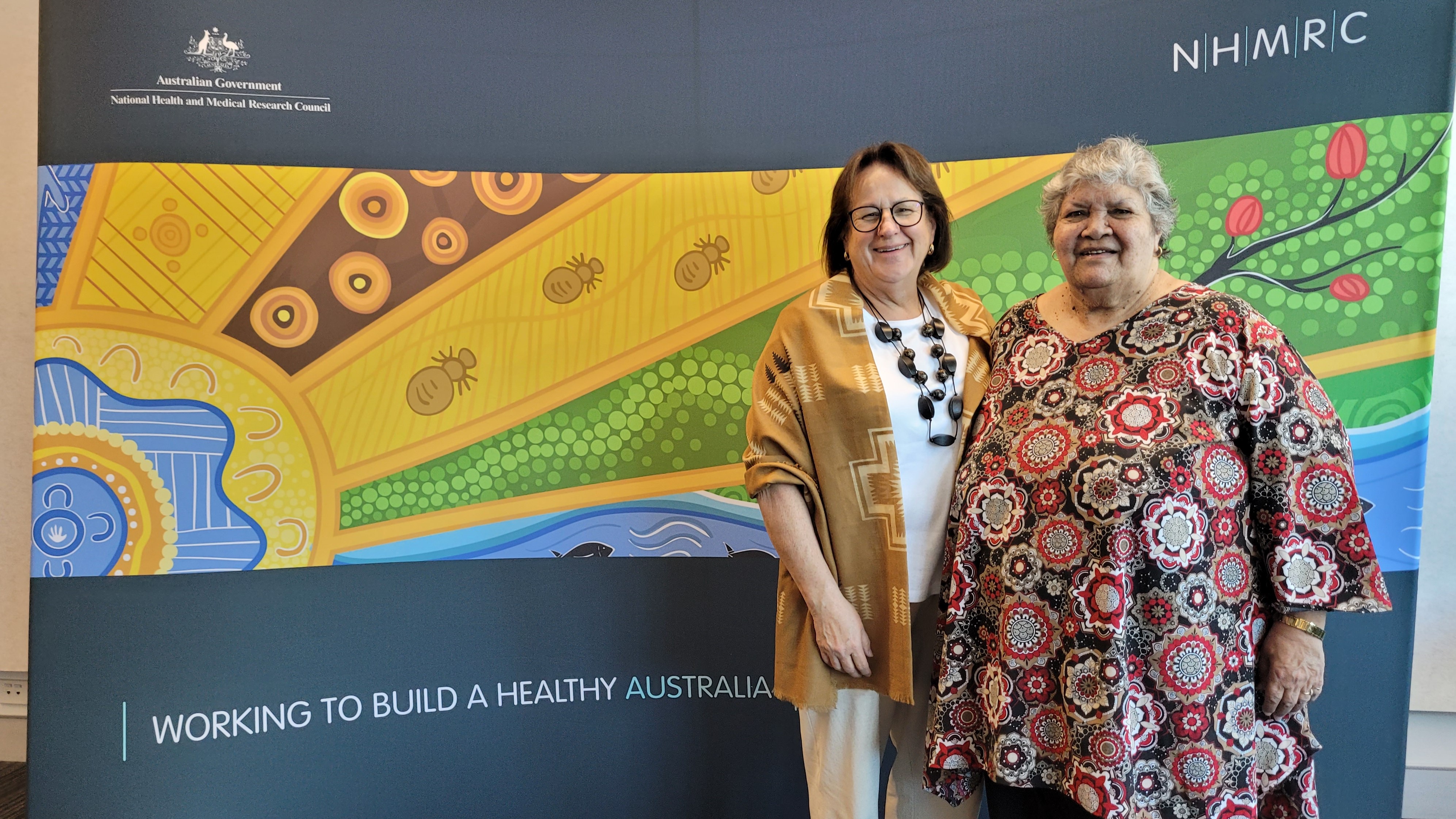 Dr Margo Greenwood and Professor Yvonne Cadet-James in front of NHMRC banner