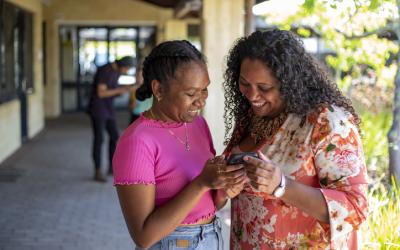 Indigenous women smiling at a mobile phone